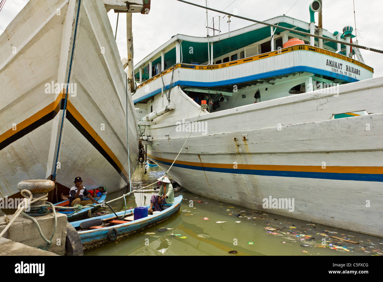 JAKARTA, INDONESIA - NOV 14 2010: Fisherman on boats resting amongst river pollution in Jakarta. Stock Photo