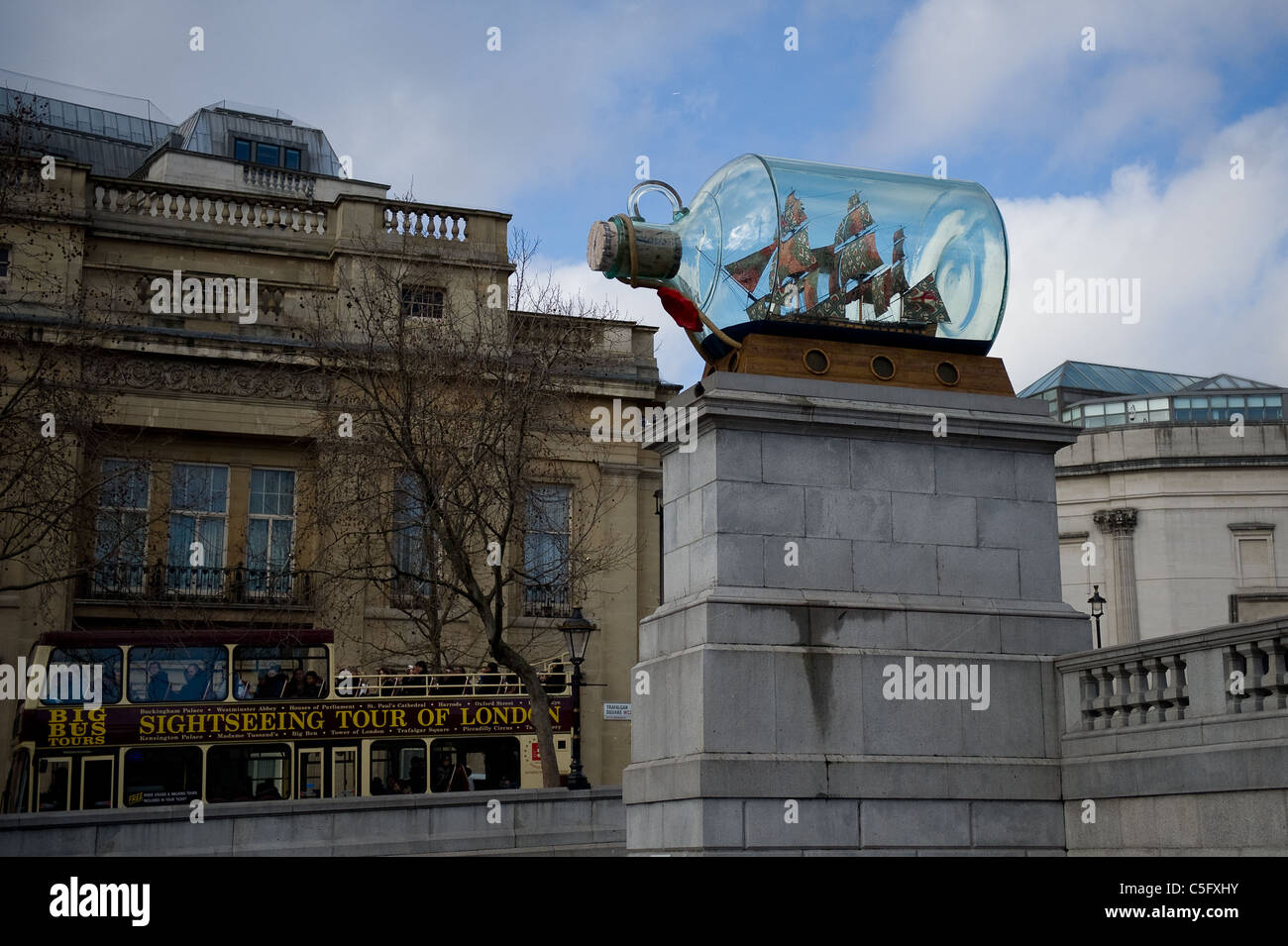 London tour bus passes 'Nelson's Ship in a Bottle' by Yinka Shonibare, the current commission on Plinth 4 in Trafalgar Square. Stock Photo
