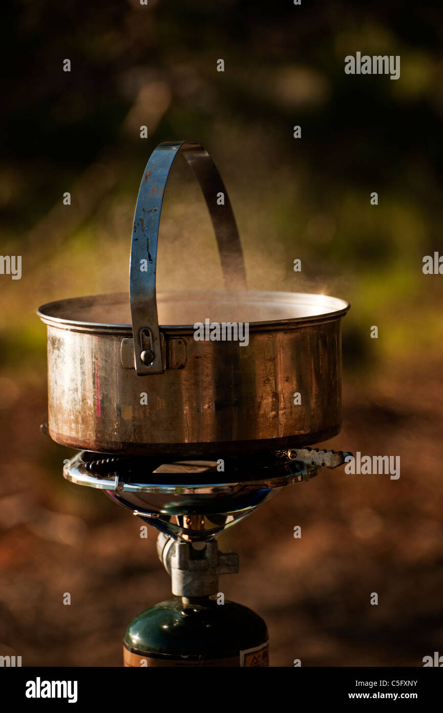 A pot of water boils over a oneburner propanefuel camping stove Stock