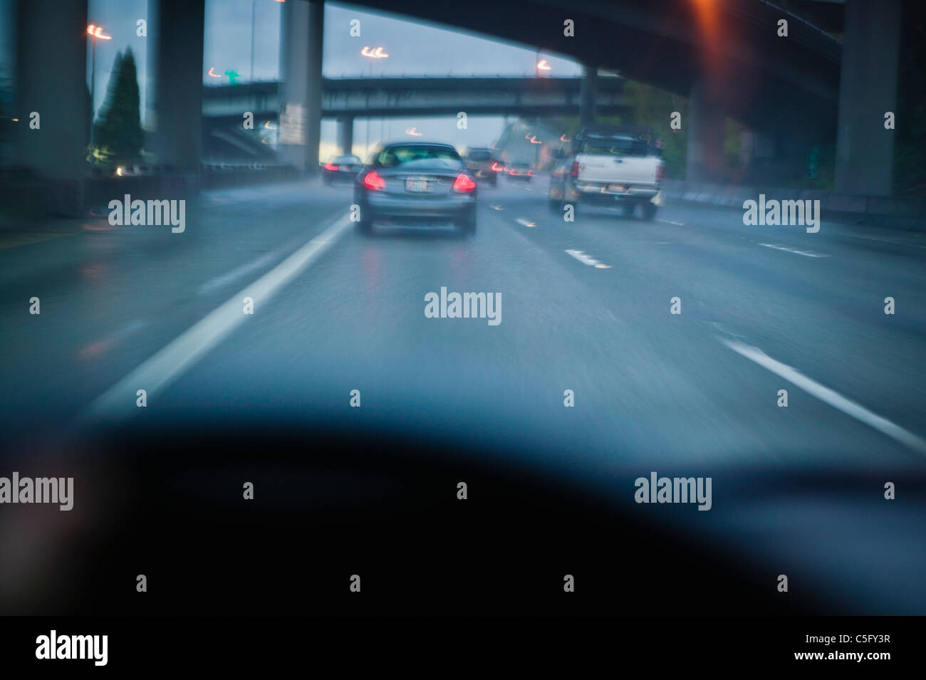 A first person view of driving on a freeway below overpasses in traffic. Stock Photo