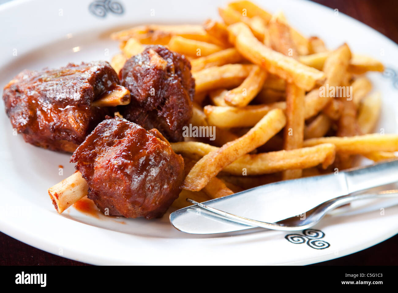 Tender pieces of fall-off-the-bone pork ribs smothered in barbecue sauce. Served with crisp hand-cut fries. Stock Photo