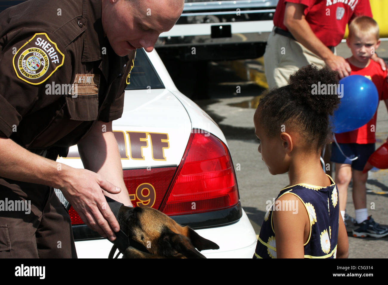 A young child looking at the K-9 dog unit and sheriff at a safety fair Stock Photo