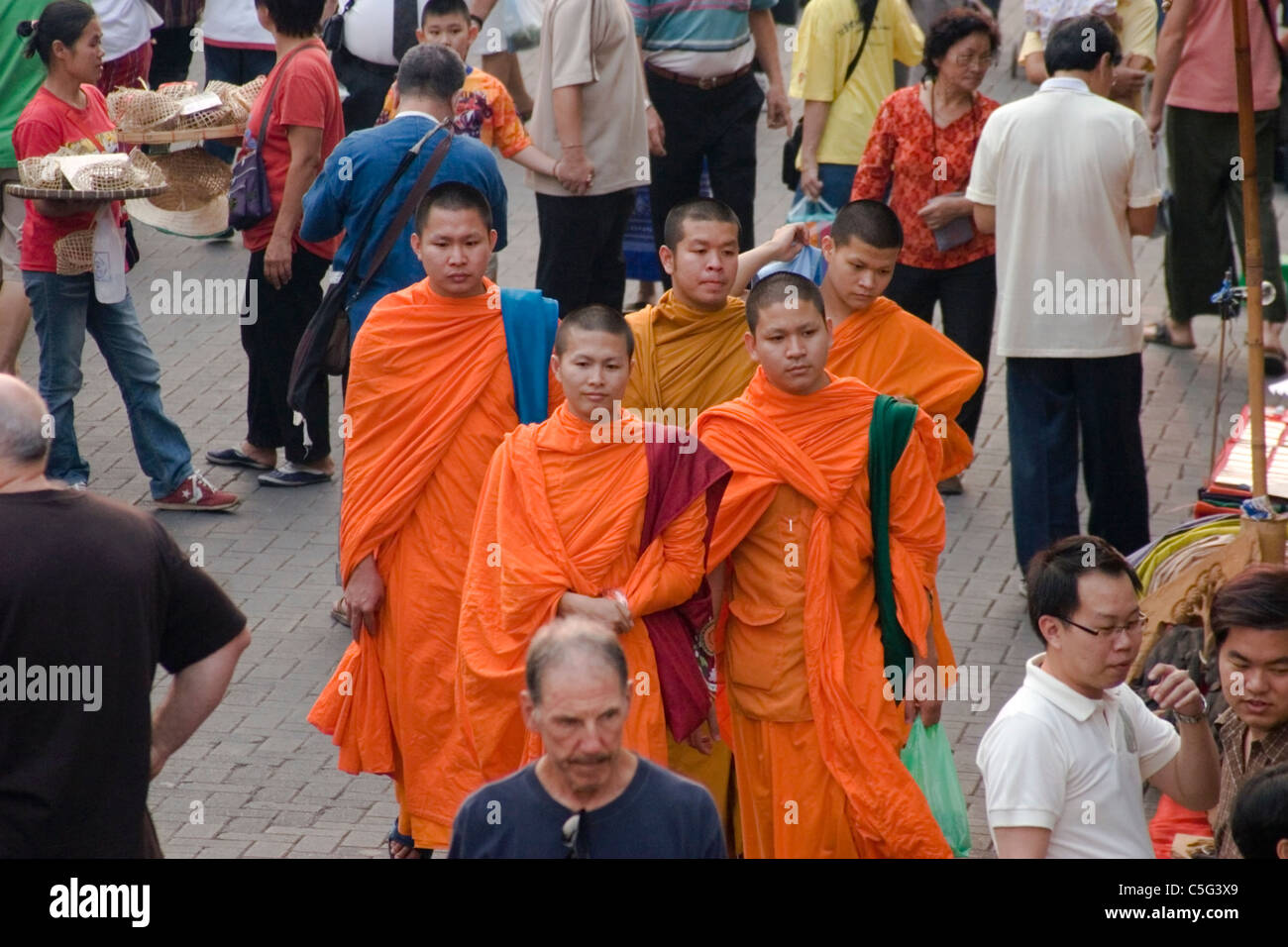 A group of Buddhist monks are shopping at a busy street market in