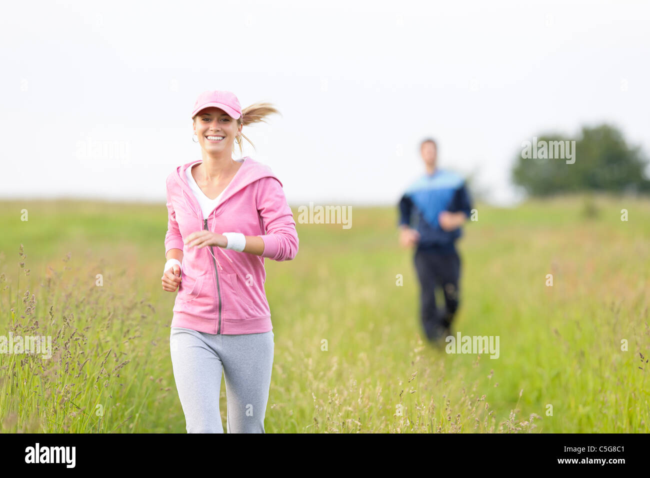 Jogging young fit couple running field meadow in sportswear tracksuit Stock Photo