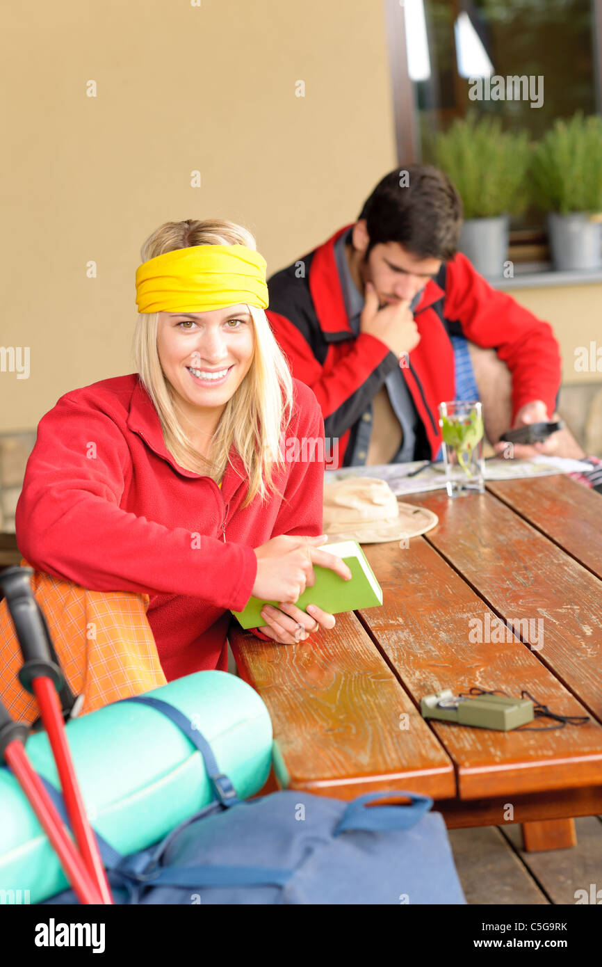 Tramping young couple backpack relax sitting by wooden table cottage
