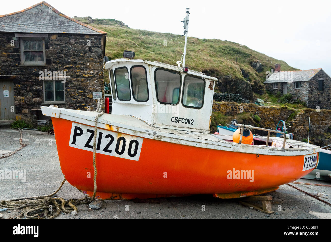 Bright orange fisherman's boat in the small traditional fishing harbour at Mullion Cove, Cornwall, UK. Stock Photo
