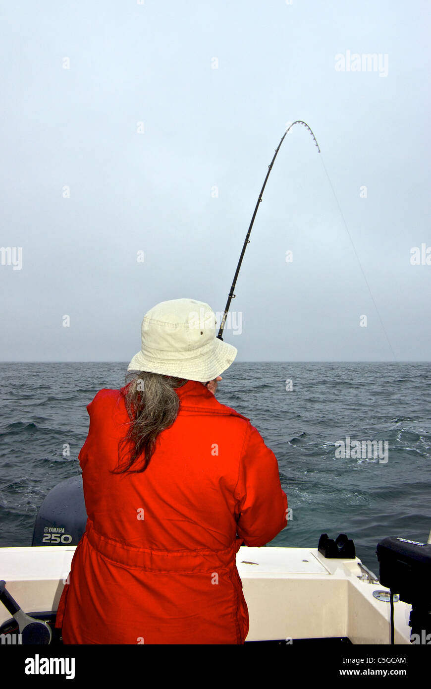 Woman angler playing Chinook salmon offshore Pacific Ocean Kyuquot BC Stock Photo