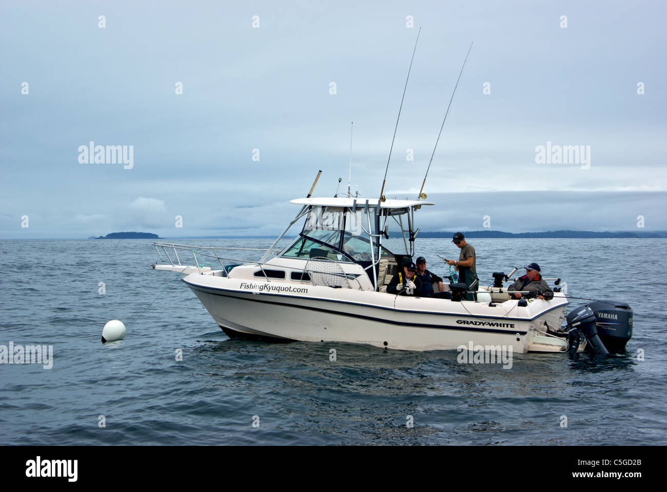 Angler playing halibut sport fisher boat fishing anchored offshore Kyuquot Sound BC Stock Photo