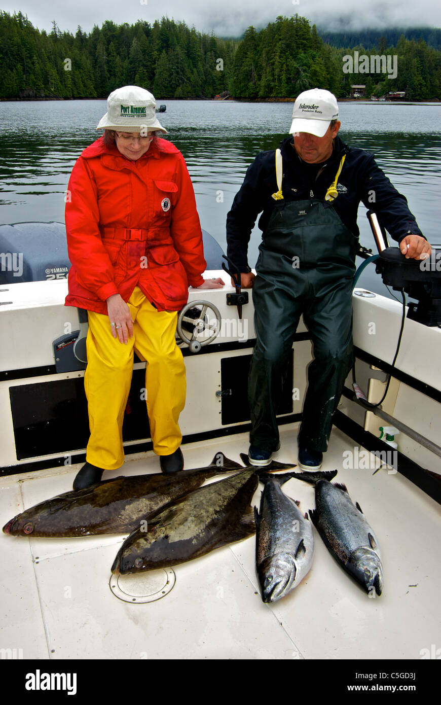 Woman angler fishing guide admiring sport fish catch Chinook salmon halibut Kyuquot Sound BC Stock Photo
