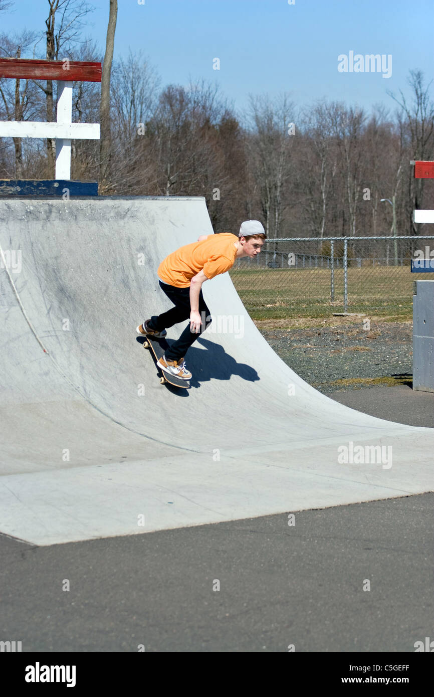 Portrait of a young skateboarder skating on a ramp at the skate park. Stock Photo