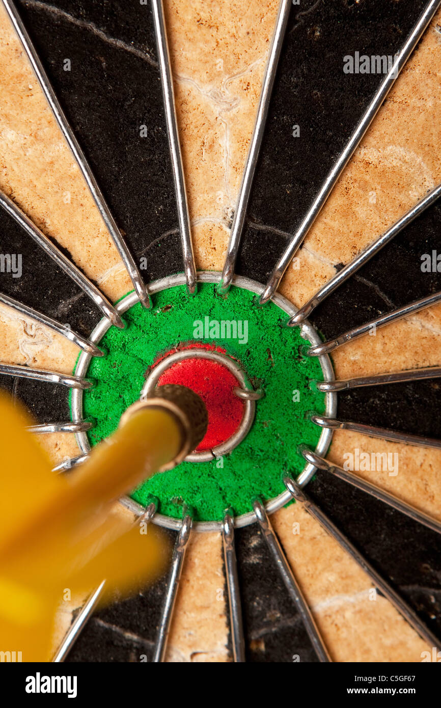 Close up of a dart that has nailed a bulls eye in the center of the dart board. Shallow depth of field. Stock Photo