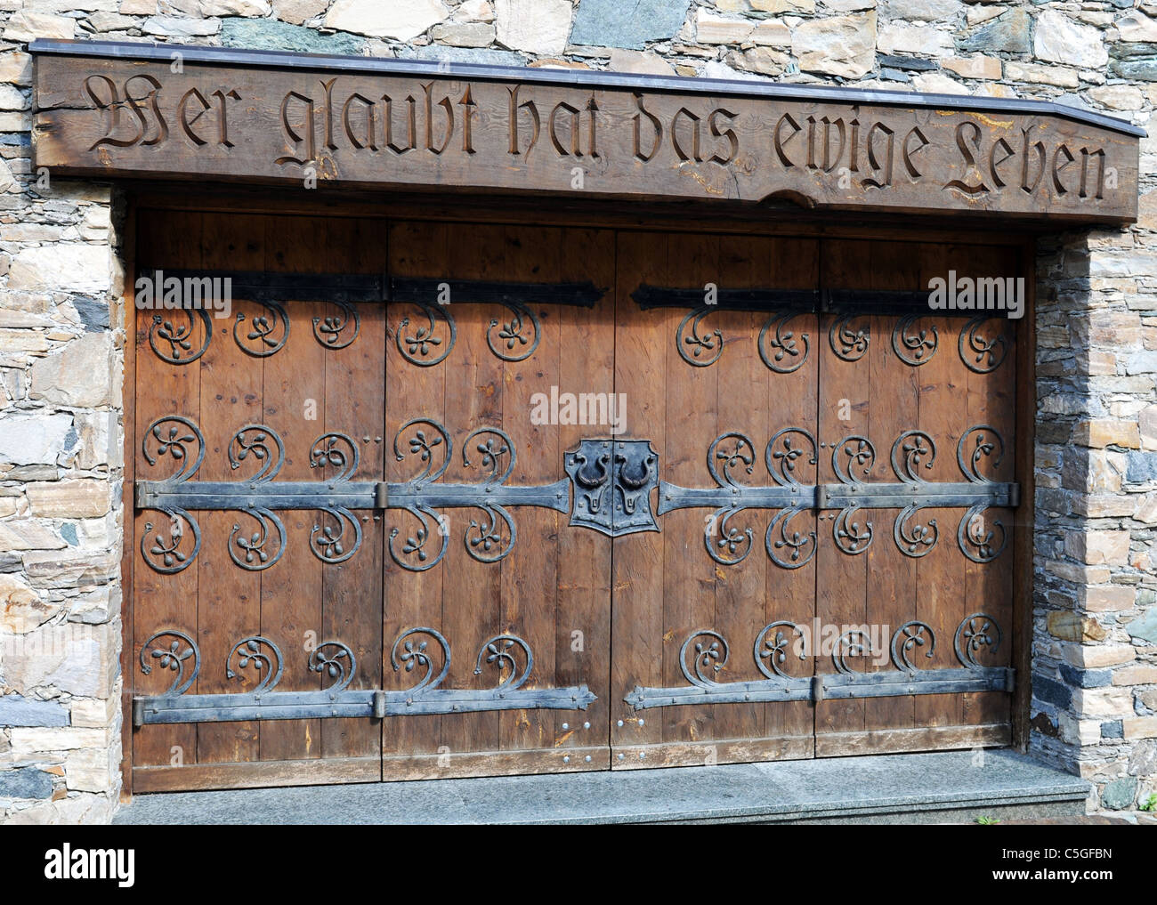 Entrance door to a christian building at Heiligenblut, Text means "Who confesses, will live forever" Stock Photo