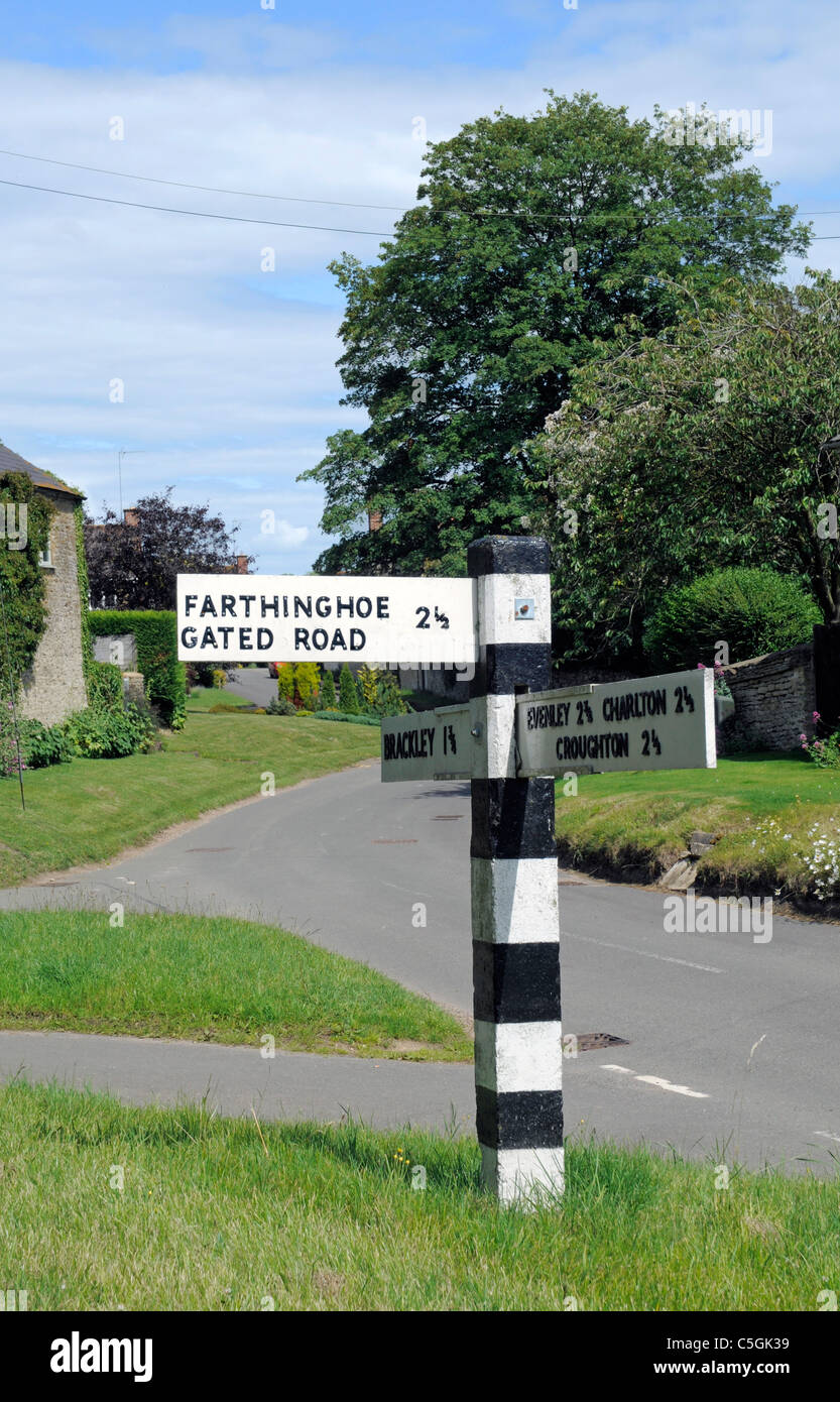 Old Black and White Road Sign in Hinton in the Hedges showing directions to Farthinghoe via a Gated Road Stock Photo