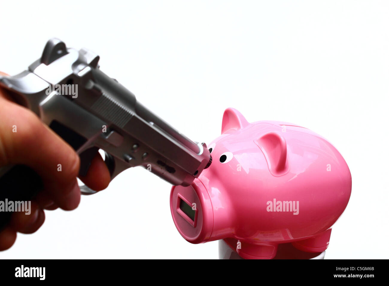 pointing a silver gun to a pink piggy bank, conceptual image for a bank robbery Stock Photo