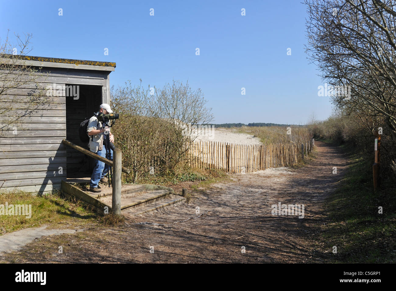 Birdwatcher with telescope leaving bird hide in the nature reserve Parc du Marquenterre at the Bay of the Somme, Picardy, France Stock Photo