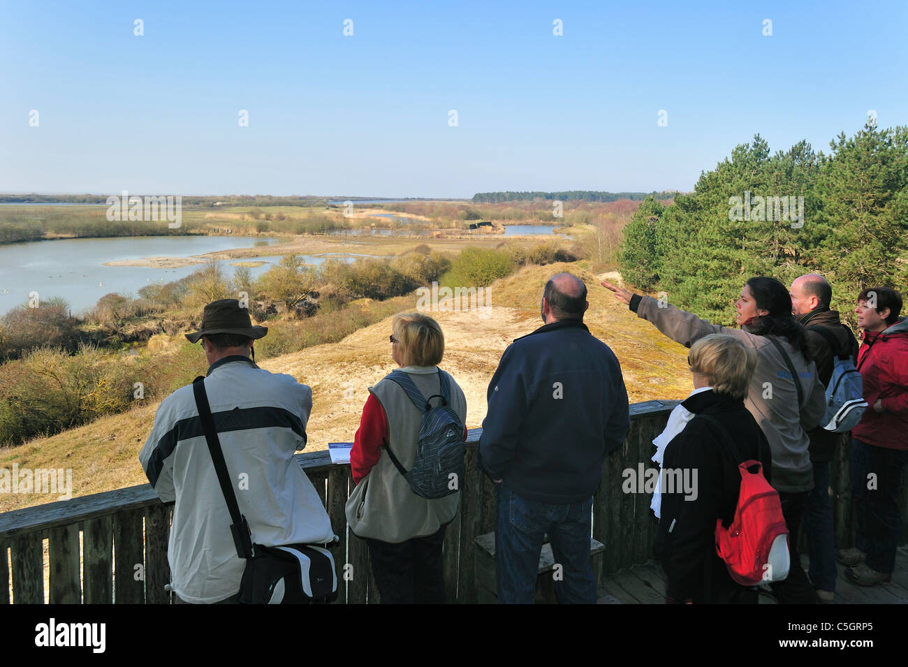 Guide with tourists on viewing platform looking over wetland of nature reserve Parc du Marquenterre, Bay of the Somme, France Stock Photo
