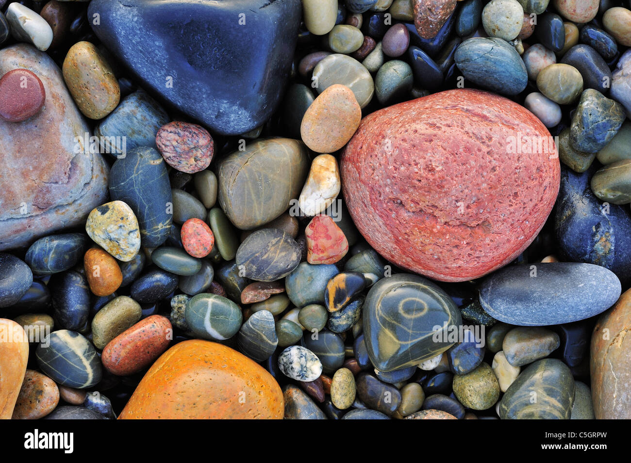 Colourful water smoothed pebbles in surf at shingle beach Stock Photo