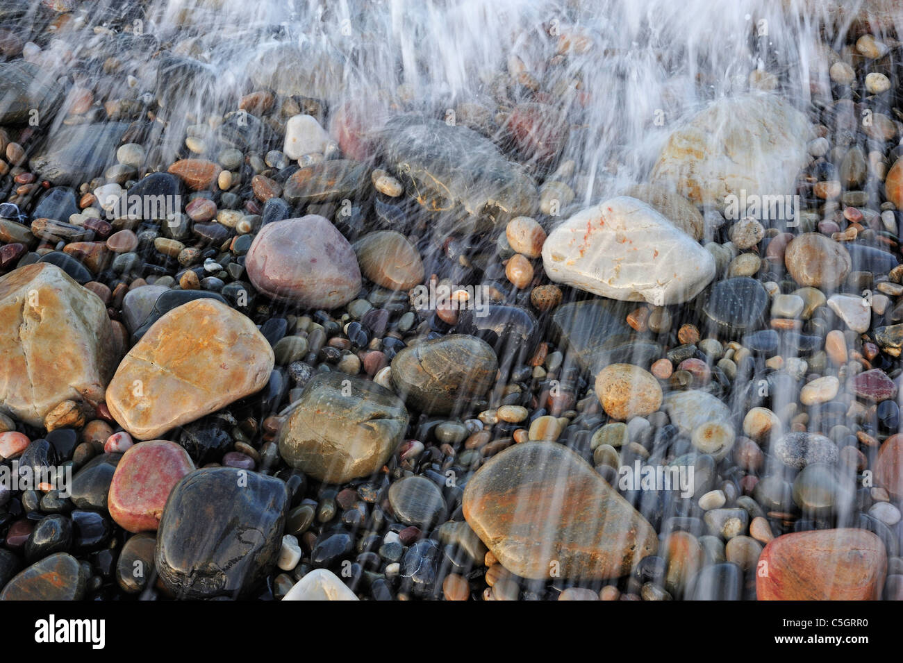 Colourful water smoothed pebbles in surf at shingle beach, Normandy, France Stock Photo