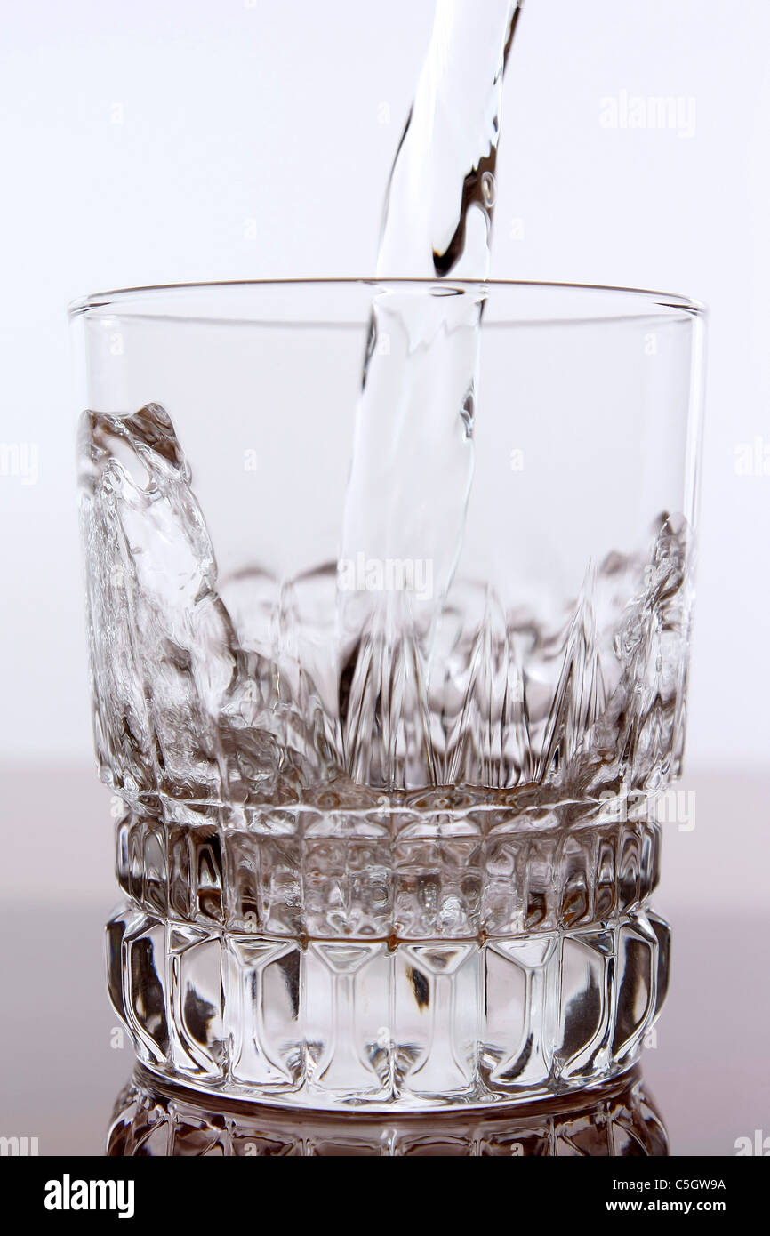 pouring water into glass with mirror reflection on the bottom Stock