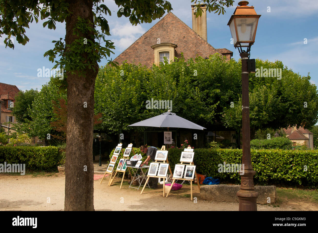 Artist arranging paintings for sale Domme Dordogne Aquitaine France