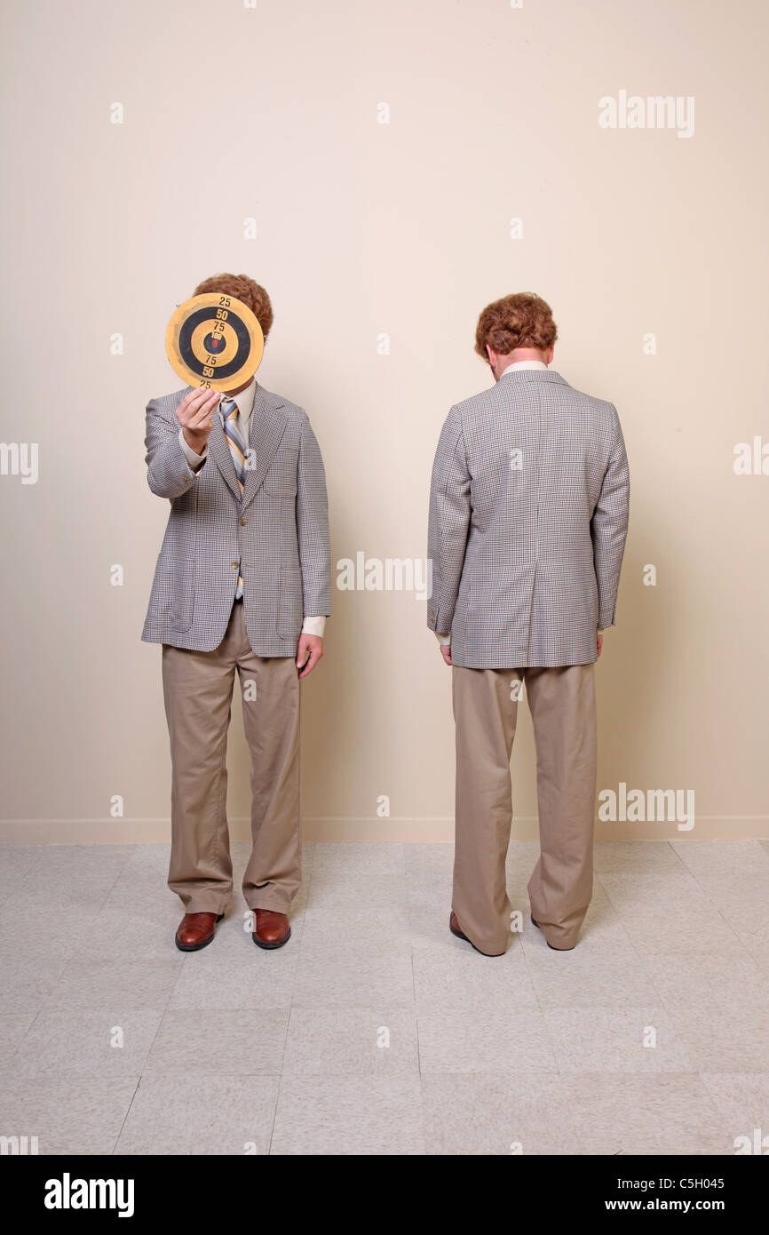 two men hiding faces, one behind a target, the other with back Stock Photo