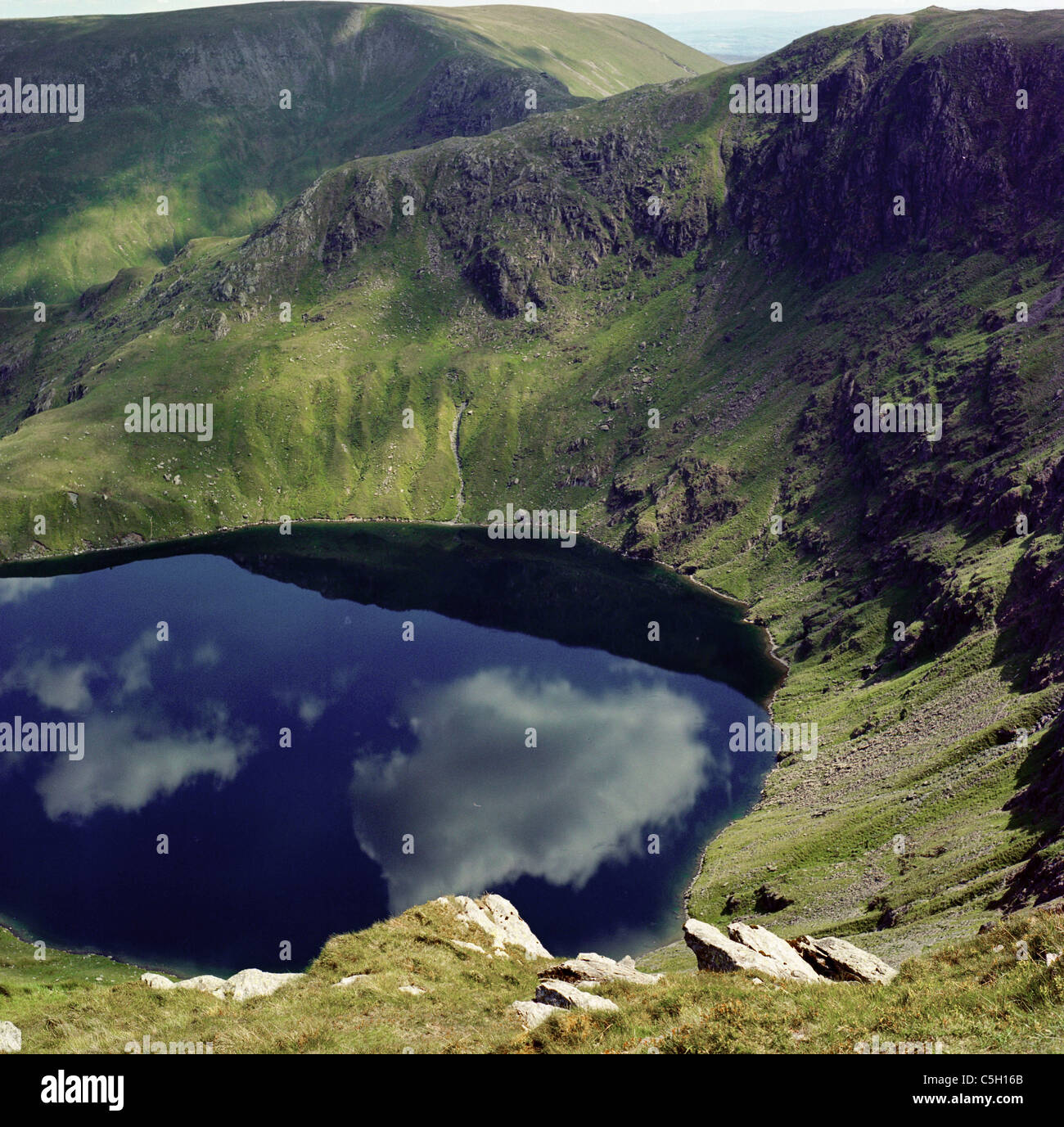 Strong reflections of clouds in the surface of Small Water in the English Lake District Stock Photo