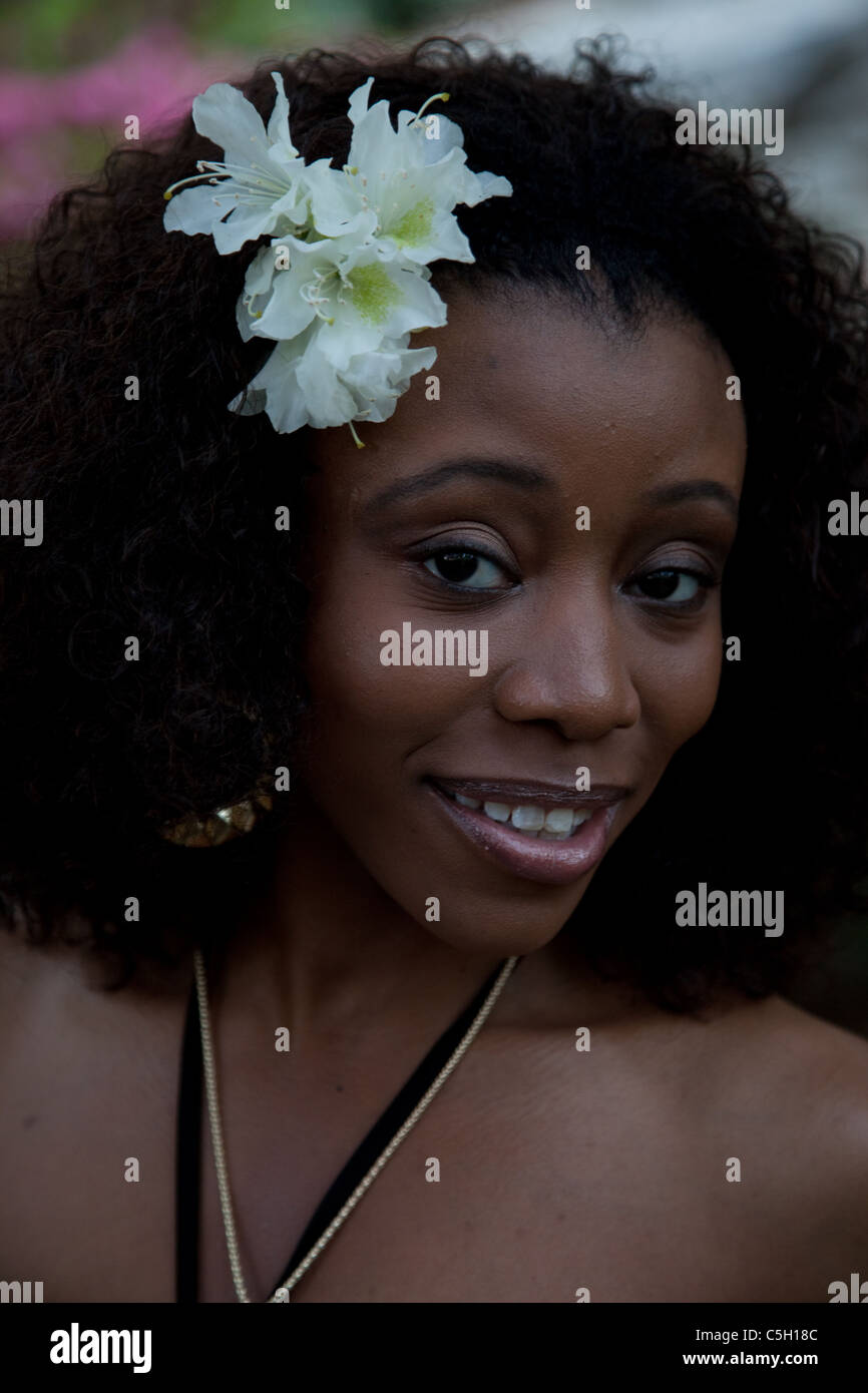 Lovely black woman with white flowers in her hair and looking at the ...