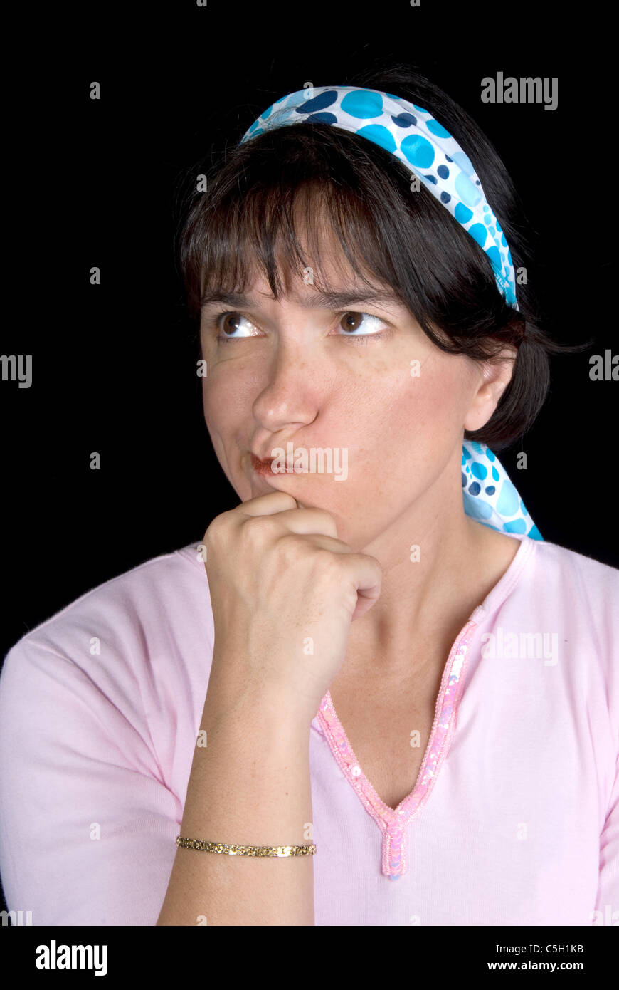 Woman pondering life. She is set off by a blue hair wrap against a black background. Stock Photo