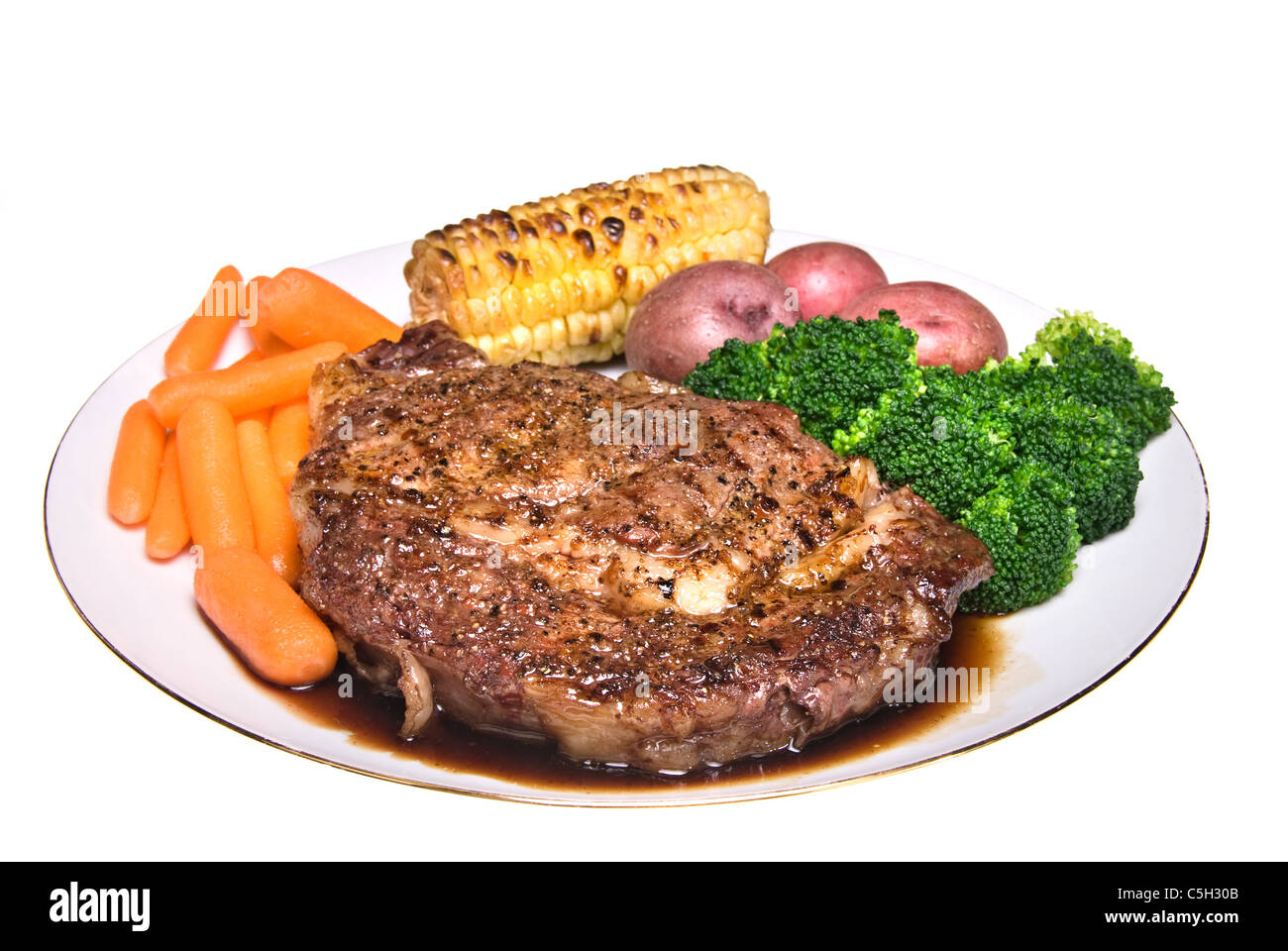 A delicious steak dinner consisting of a fillet, baby carrots, broccoli; baby potatoes and corn on the cob. Stock Photo