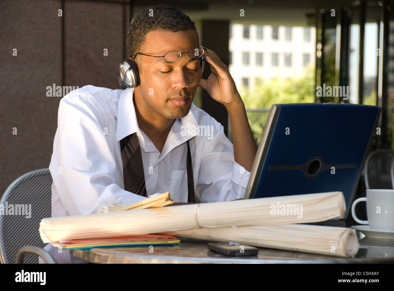 An executive engineer conducting work during his lunch hour decides to take a break and listen to some music. Stock Photo