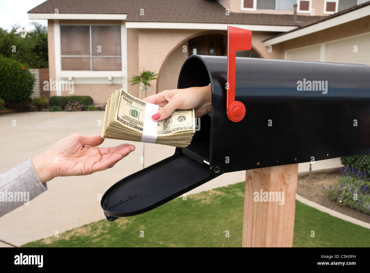 A bundle of cash is being delivered to a homeowner waiting for an economic stimulus payment or property bailout money. Stock Photo