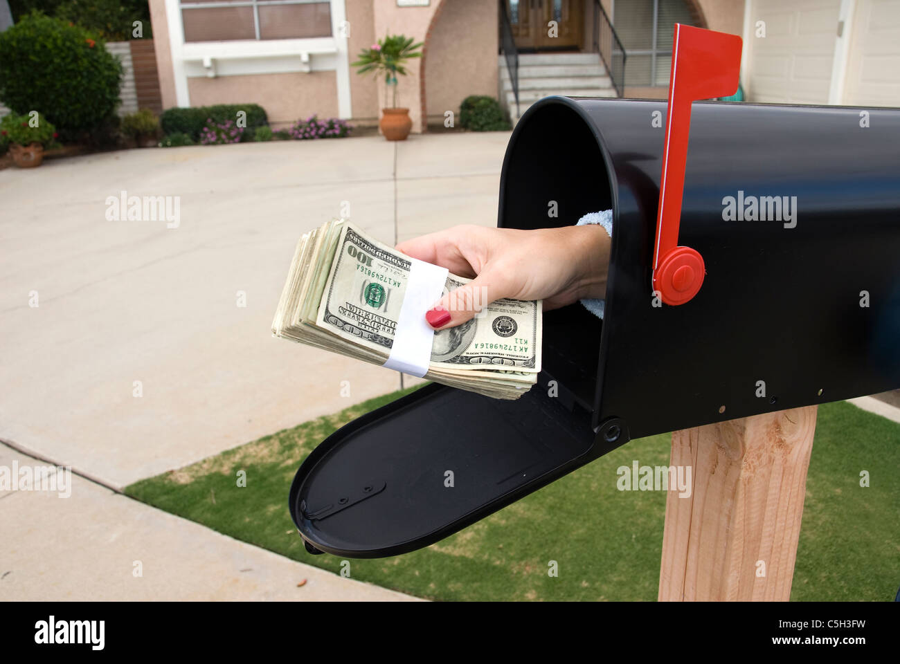 A bundle of cash is being delivered to a homeowner waiting for an economic stimulus payment or foreclosure bailout. Stock Photo