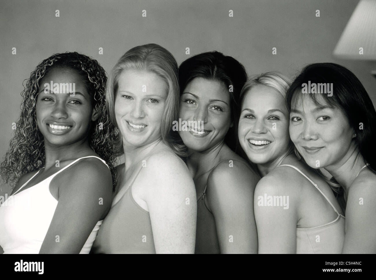 Ethnic mixture of five female friends smiling at camera in black and white Stock Photo