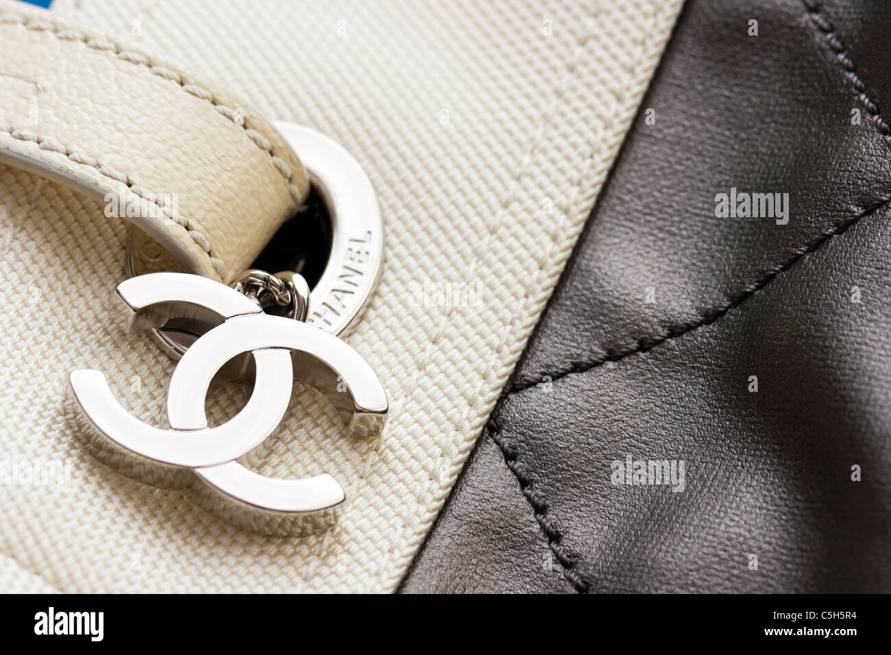 The accent of a Chanel designer tote bag. Two intertwined letter Cs hanging  from the strap as it threats through the Belt loop, itself marked 'Chanel'  Stock Photo - Alamy