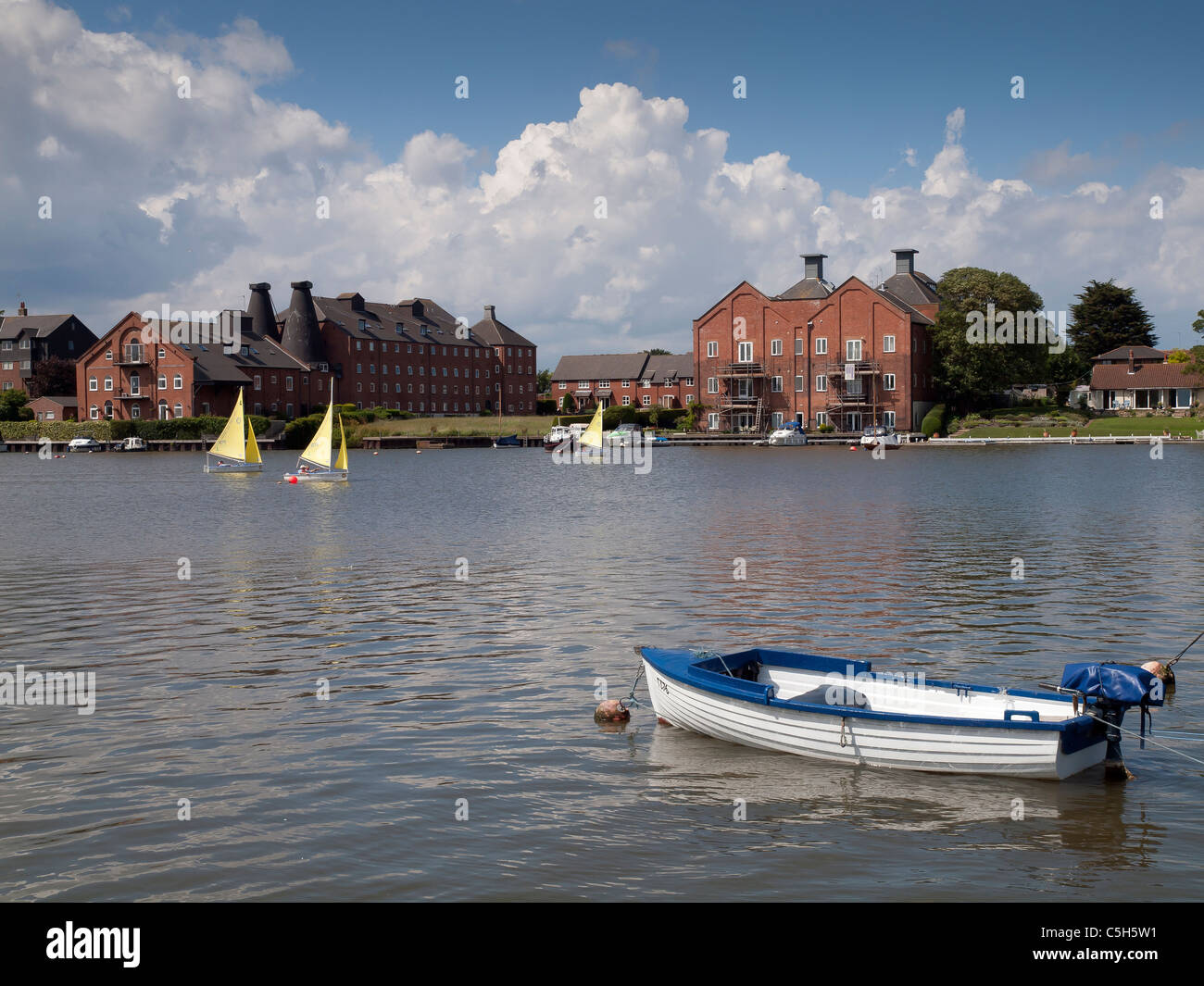 Small Rotary Club sailing boats racing on the River Waveney in front of smart apartment blocks at Oulton Broad Stock Photo
