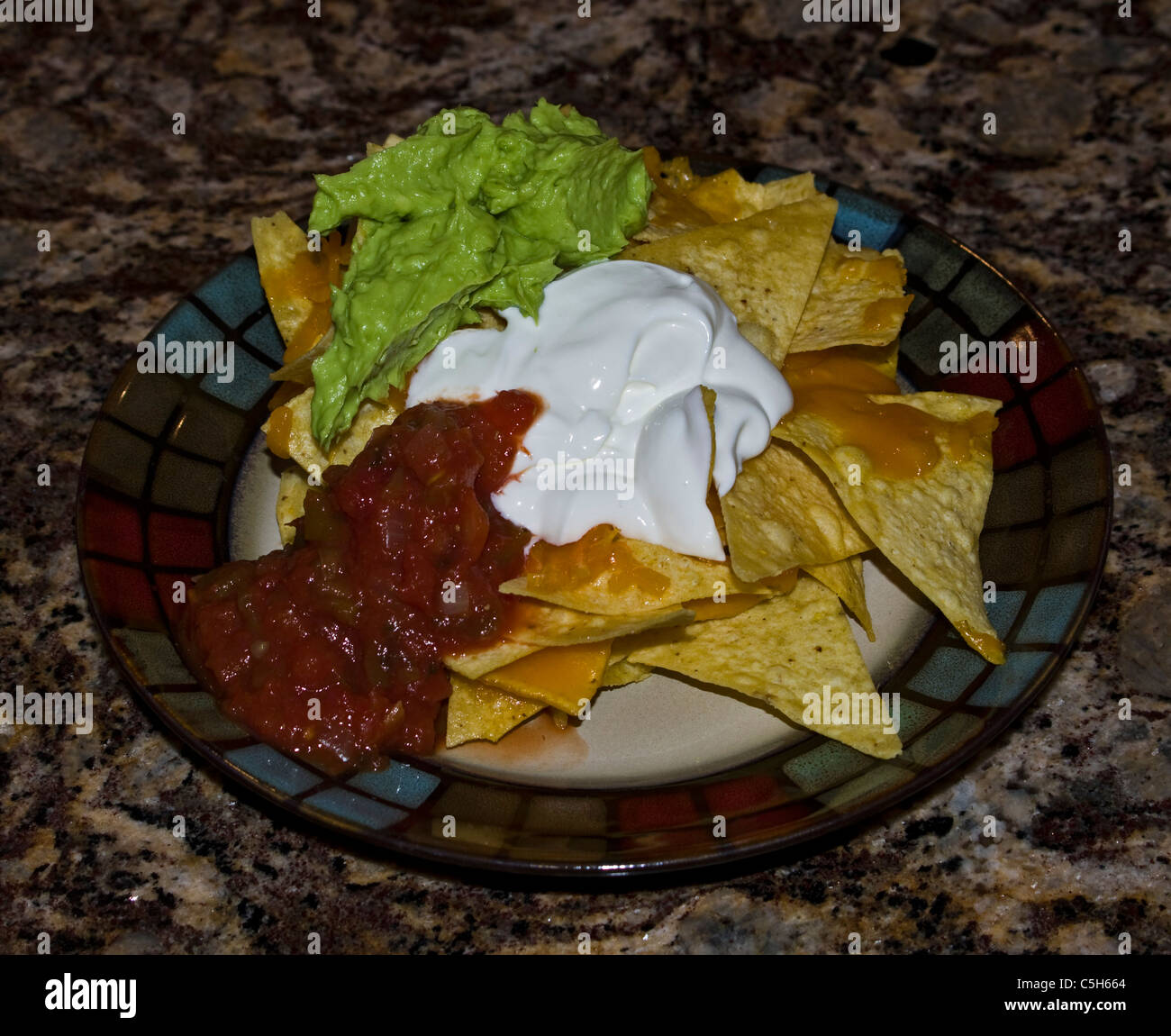 Nacho chips with salsa , sour cream, chedder cheese and guacamole Stock