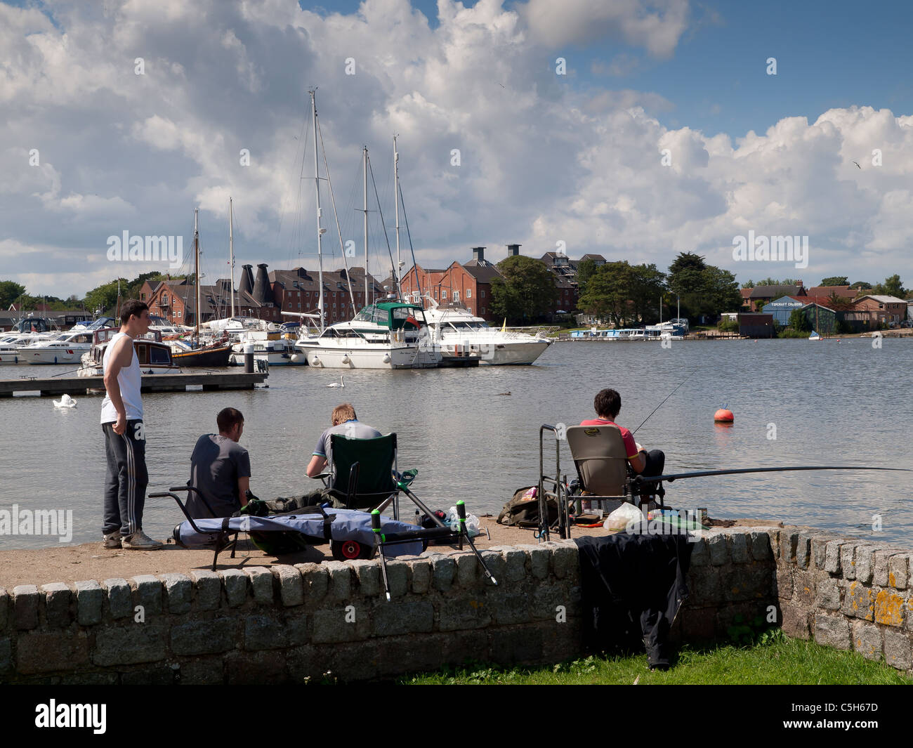 A group of young men fishing in the River Waveney at Oulton Broad Suffolk Stock Photo