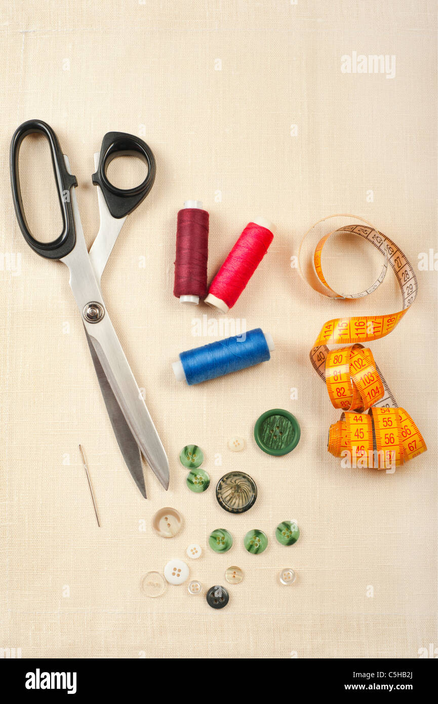 Sewing supplies. Set from measuring tape, buttons, bobbins of thread, needle and scissors on linen canvas Stock Photo