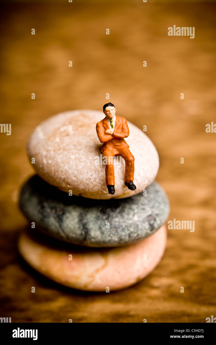 man figurine sitting on a stone, solitude concept Stock Photo