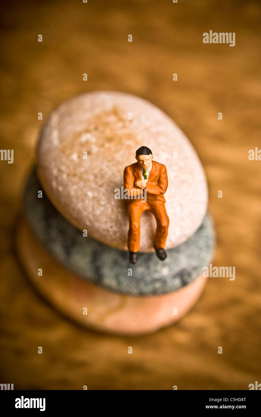 man figurine sitting on a stone, solitude concept Stock Photo