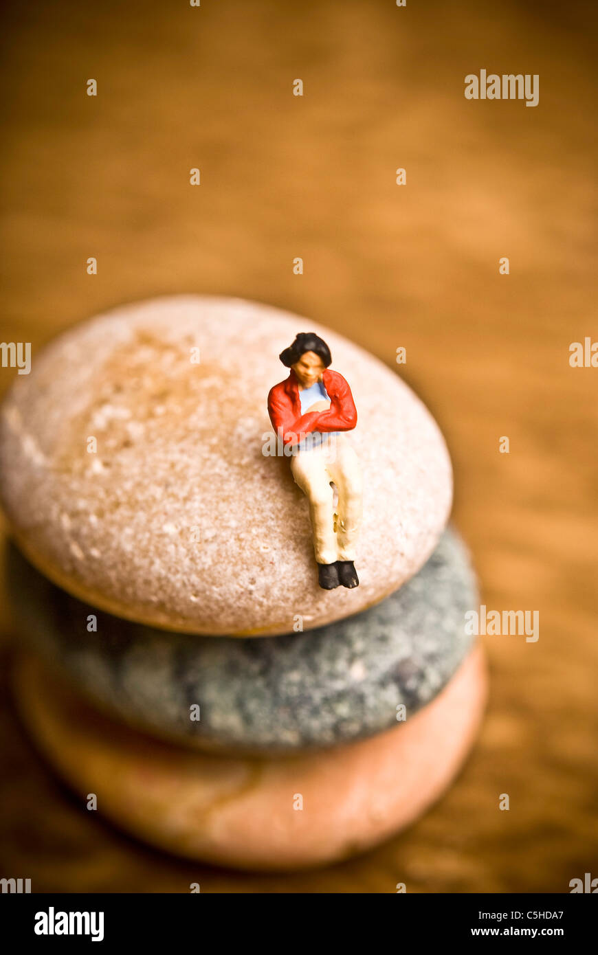 woman figurine sitting on a stone, solitude concept Stock Photo