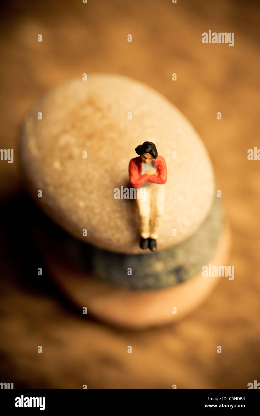 woman figurine sitting on a stone, solitude concept Stock Photo