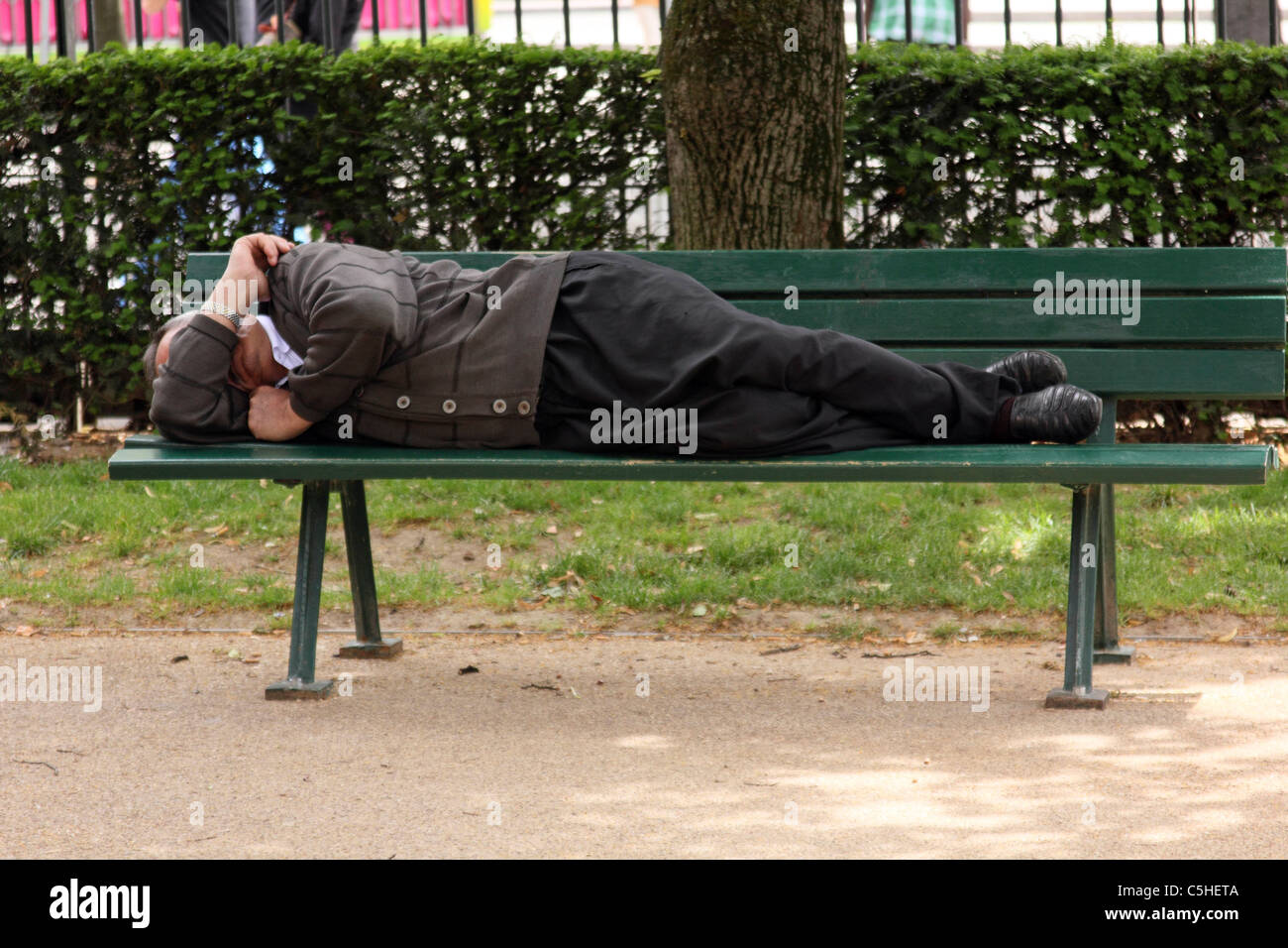 Man sleeping on a Paris park bench Stock Photo