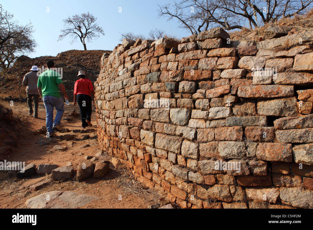 Visitors walk past a wall within the Khami UNESCO World Heritage Site