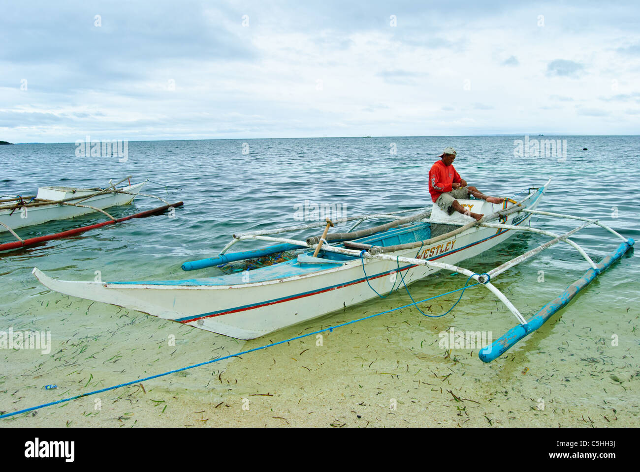 A fisherman's busy with fishing nets on his outrigger canoe, Malapascua  Stock Photo - Alamy
