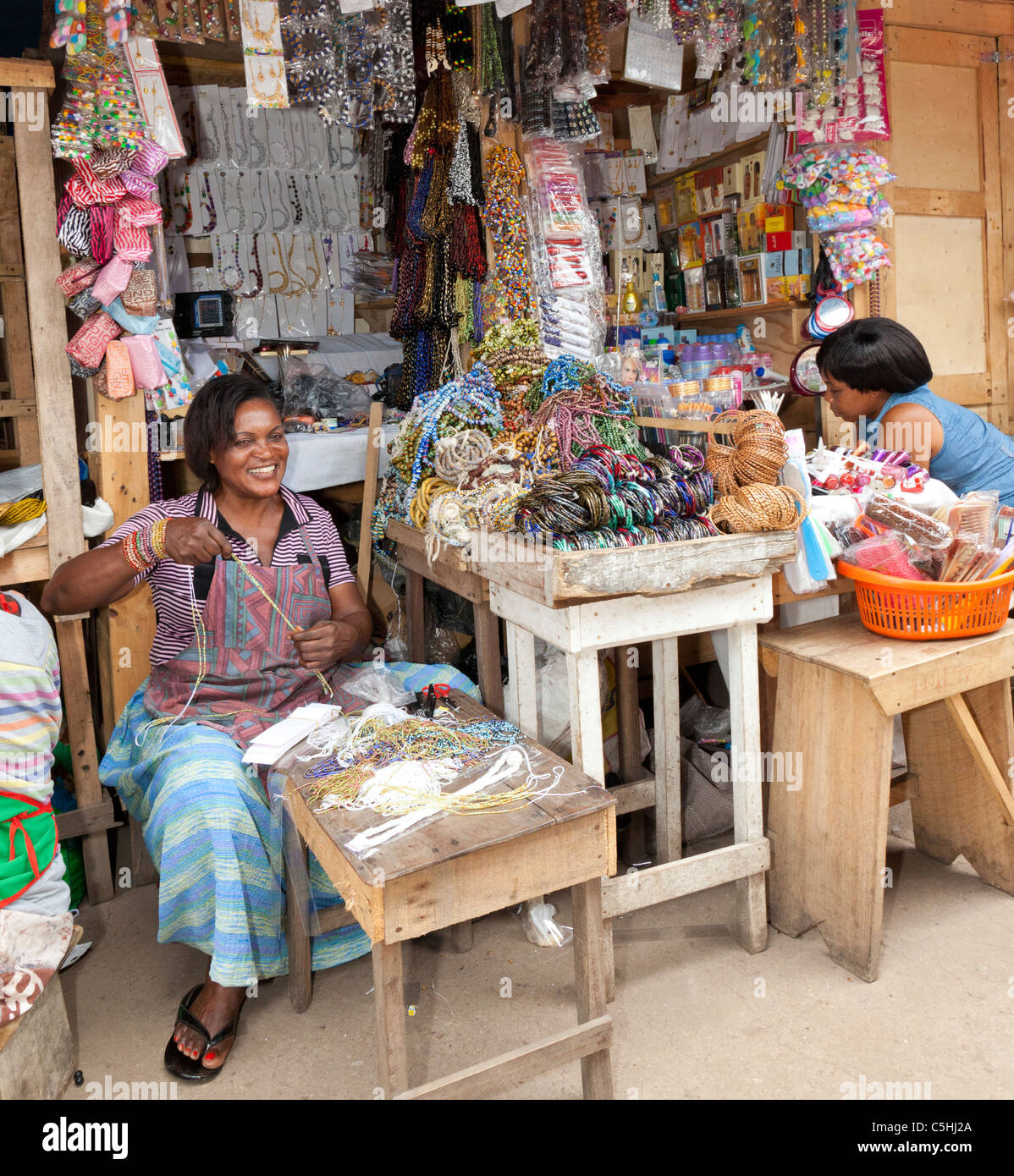 An African market trader making jewelry at a market stall. Makola Stock