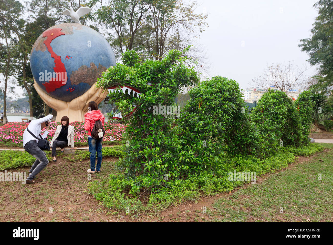 Dragon topiary sits by globe of the world in front of Hoan Kiem Lake in the historical center of Hanoi, Vietnam. Stock Photo