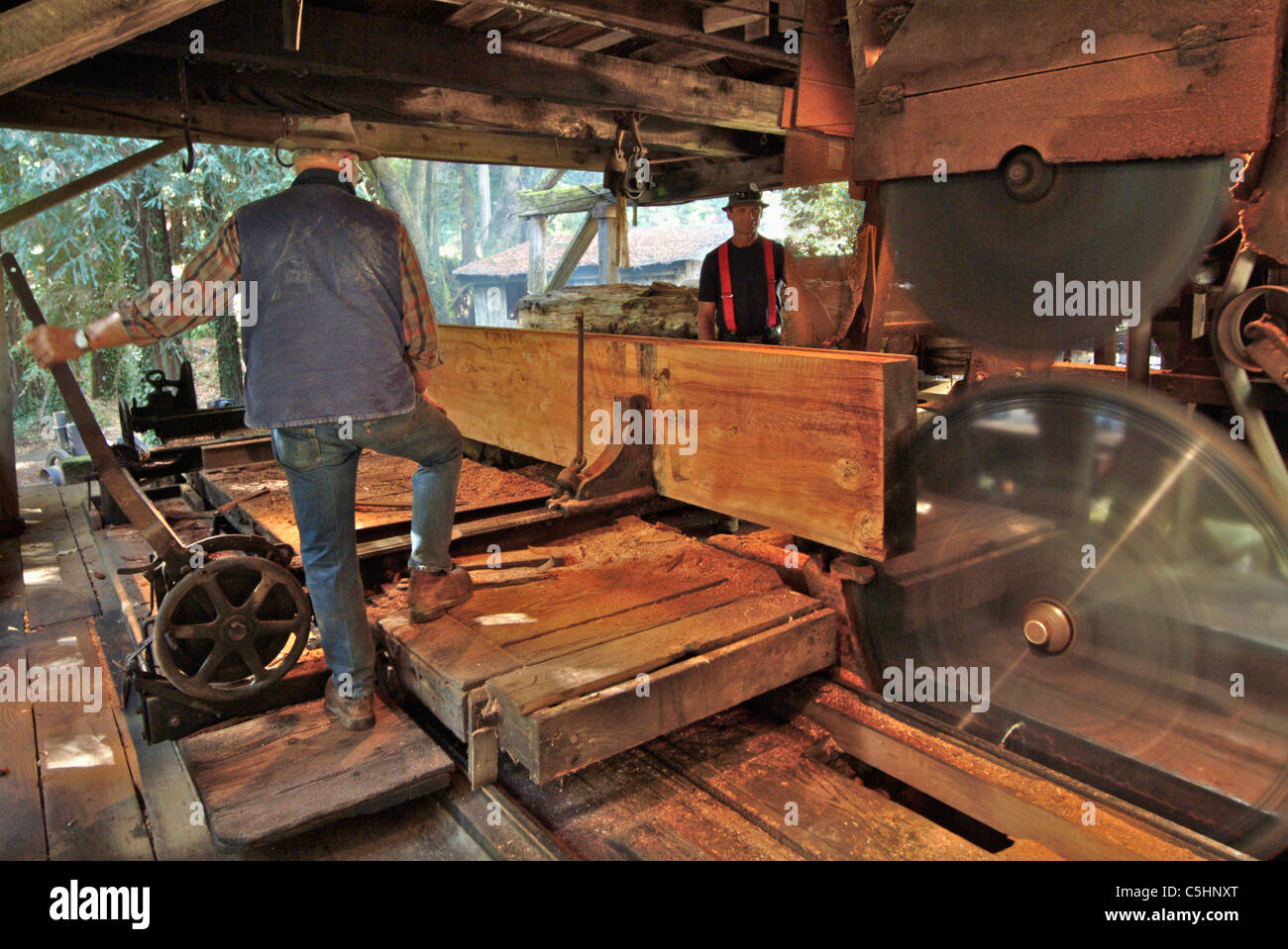 Saw mill worker are making the last cut on the trimmed redwood log at an antique saw mill in Occidental California Stock Photo
