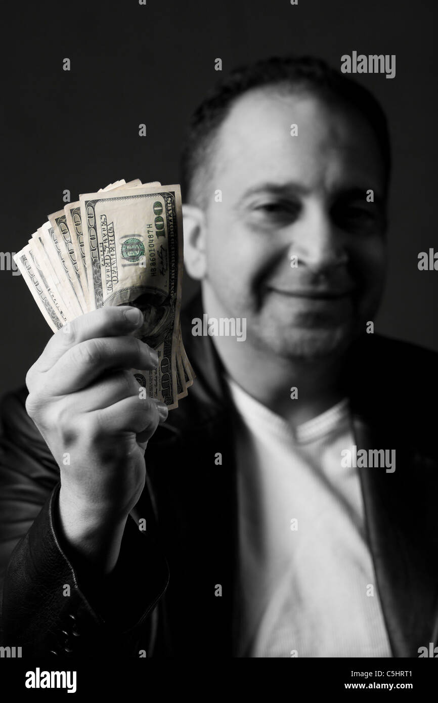 A happy man holds a handful of green American money with selective color. Stock Photo