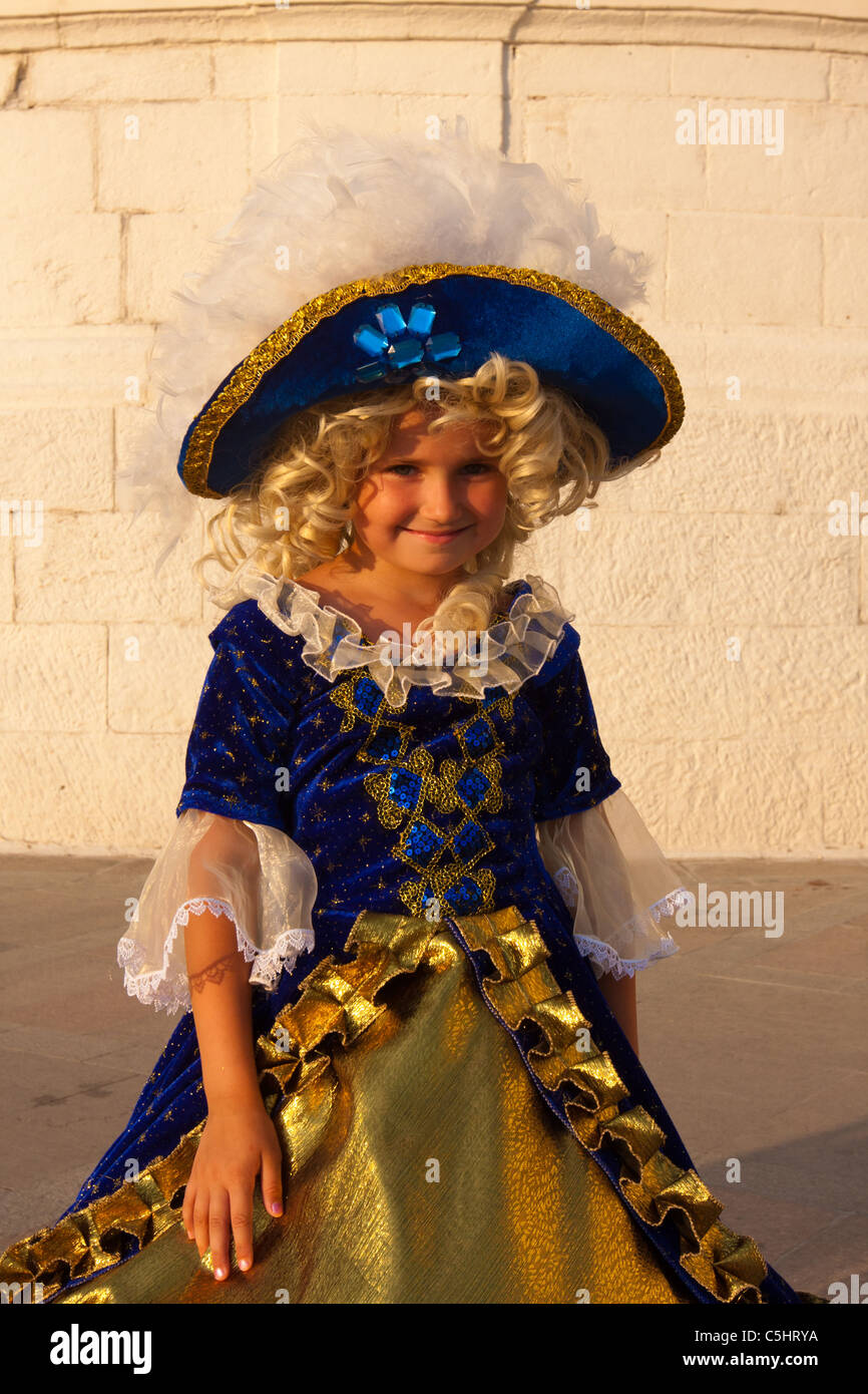 8-9 year old girl in crinoline. Small smiling girl in royal costume with a big hat. Stock Photo
